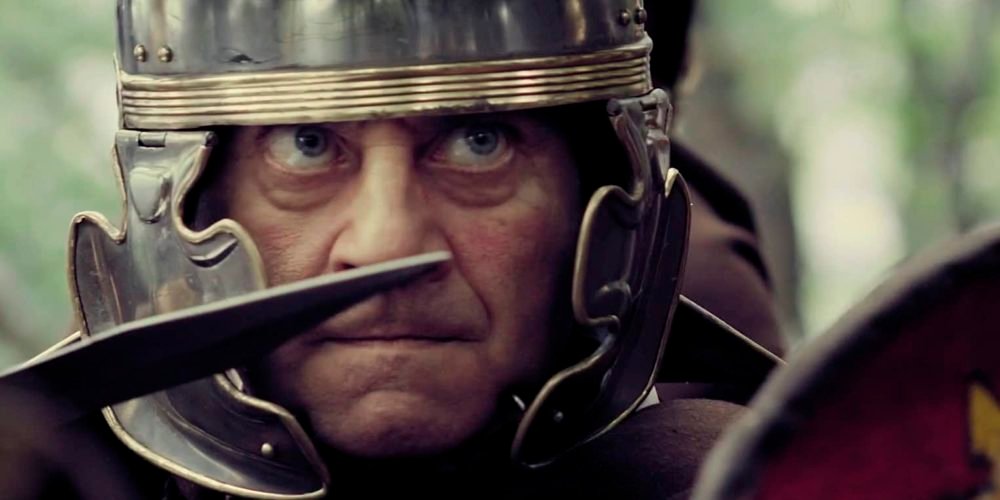 Fotograma del reel de Iliada Films: primer plano de un legionario romano con casco durante un rodaje, con el logotipo de Iliada Films superpuesto